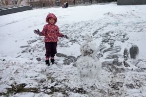 Girl near a snowman in a park in Kyiv