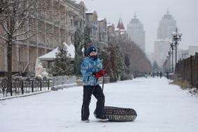 Мальчик с тюбингом на заснеженной улице в Киеве