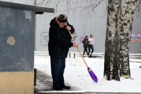 A woman clears snow from a path near a residential building in Kyiv