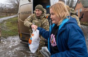 Жінка отримує продуктовий набір у прифронтовому селі на Харківщині