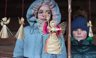 Дети рассматривают соломенного Рождественского ангела