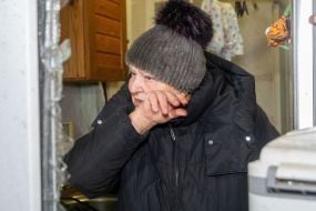 Woman cleaning up broken glass in an apartment damaged by Russian shelling