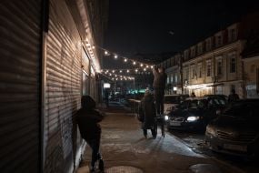 People install LED string lights on an unlit street in Kyiv