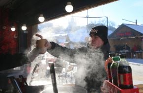 Мужчина покупает глинтвейн на Контрактовой площади в Киеве