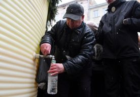 People collect holy water from a large reservoir on Rynok Square in Lviv