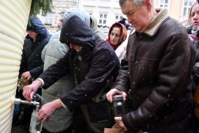 People collect holy water from a large reservoir on Rynok Square in Lviv