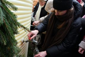 People collect holy water from a large reservoir on Rynok Square in Lviv