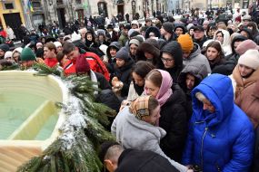 People collect holy water from a large reservoir on Rynok Square in Lviv