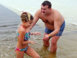 Девочка с отцом купаются в проруби