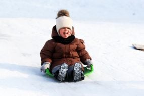 A girl sledding down a snowy hill
