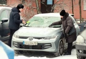 People clear snow from a car