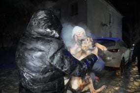 Жители с собакой эвакуируются из жилого дома после атаки БПЛА в Харькове