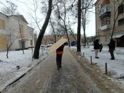 Мужчина несет фанеру, чтобы забить выбитые окна в квартире, после атаки БпЛА в Харькове