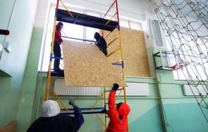 Covering up broken windows in a school gym with plywood after Russian shelling