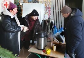 Residents of a damaged residential building drink tea.