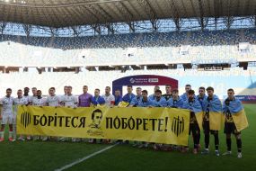 Players of FC Rukh and FC Metalist 1925 hold a poster "Fight - you will win"