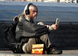 Teenage girl listening to music while sitting on a parapet