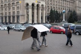 A man carries a large sheet of cardboard on his head