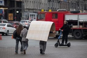 A man carries a large sheet of cardboard on his head