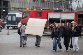 A man carries a large sheet of cardboard on his head