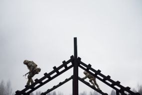 Military recruits overcome an obstacle course
