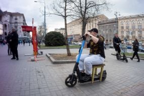 Мужчина сидит на стуле на электросамокате