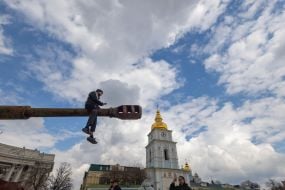 A boy sits astride the barrel of a destroyed Russian tank