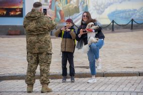 A serviceman photographs a woman and a boy near St. Michael's Cathedral in Kyiv
