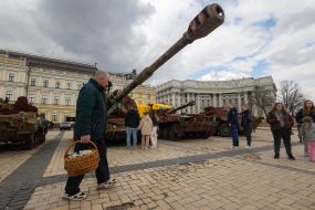 Believers with Easter baskets against the backdrop of destroyed Russian military equipment