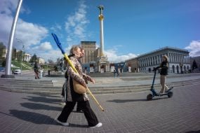 A passerby with a Ukrainian flag and a girl on an electric scooter
