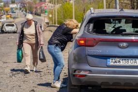Жінка біля пошкодженого внаслідок ракетного удару автомобіля