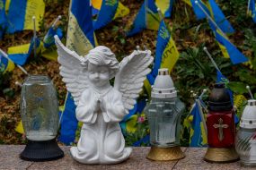 Статуя ангела возле лампадок на фоне флажков с именами погибших украинских военных