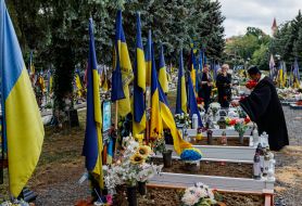 Священнослужитель возлагает цветы к могилам погибших защитников Украины
