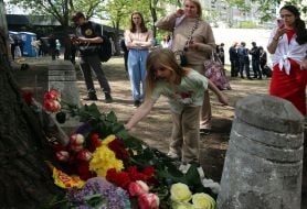 People carry flowers and toys to a house in the Darnytskyi district of Kyiv that was hit by a Russian missile