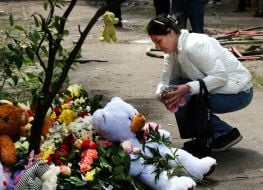 People carry flowers and toys to a house in the Darnytskyi district of Kyiv that was hit by a Russian missile