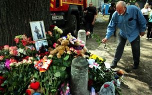 People carry flowers and toys to a house in the Darnytskyi district of Kyiv that was hit by a Russian missile