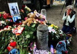 People carry flowers and toys to a house in the Darnytskyi district of Kyiv that was hit by a Russian missile