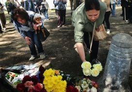 People carry flowers and toys to a house in the Darnytskyi district of Kyiv that was hit by a Russian missile