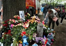 People carry flowers and toys to a house in the Darnytskyi district of Kyiv that was hit by a Russian missile