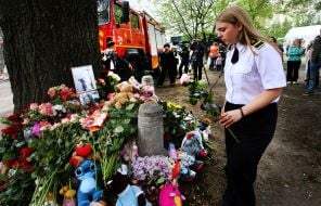 People carry flowers and toys to a house in the Darnytskyi district of Kyiv that was hit by a Russian missile