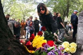 People carry flowers and toys to a house in the Darnytskyi district of Kyiv that was hit by a Russian missile