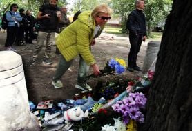 People carry flowers and toys to a house in the Darnytskyi district of Kyiv that was hit by a Russian missile