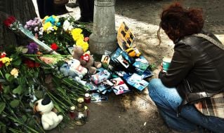 People carry flowers and toys to a house in the Darnytskyi district of Kyiv that was hit by a Russian missile