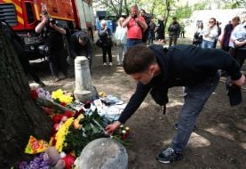 People carry flowers and toys to a house in the Darnytskyi district of Kyiv that was hit by a Russian missile