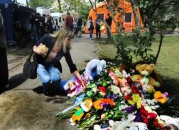 People carry flowers and toys to a house in the Darnytskyi district of Kyiv that was hit by a Russian missile