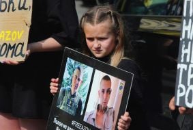 Дівчинка з фотографіями українських військовополонених захисників Азовсталі в руках