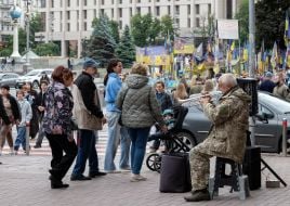 Пожилой уличный музыкант в военной форме