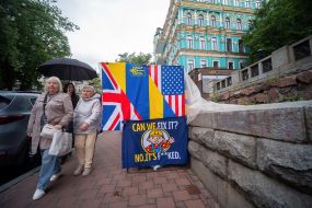 A poster with the ironic inscription "Can we fix this? No. It's already completely broken" next to the Ukrainian, British and American flags