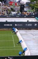 Staff covers the tennis court from the rain