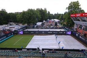 Staff covers the tennis court from the rain